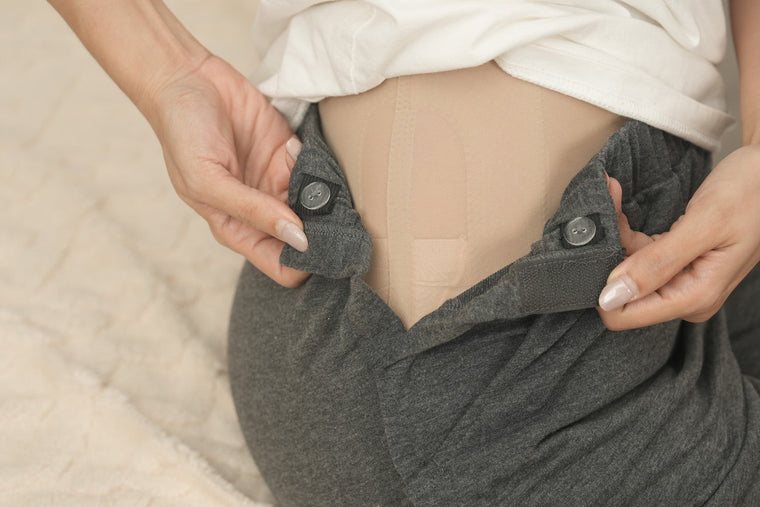 Woman seated at home in loose lounge pants, gently adjusting the waistband.