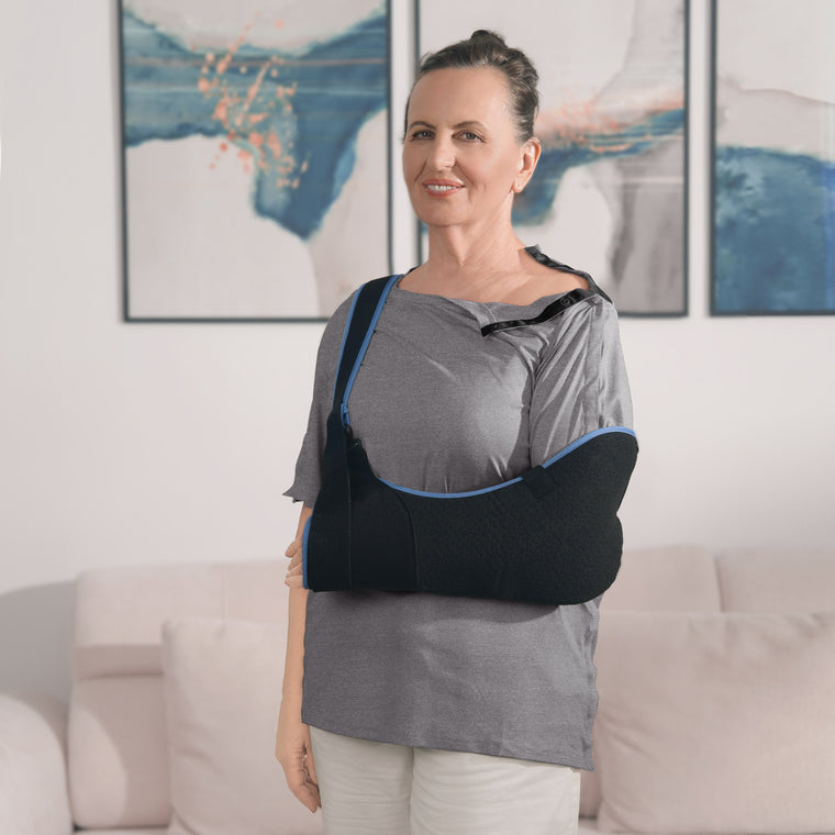 Woman wearing a Gray side-snap shirt with shoulder snaps open and an arm sling