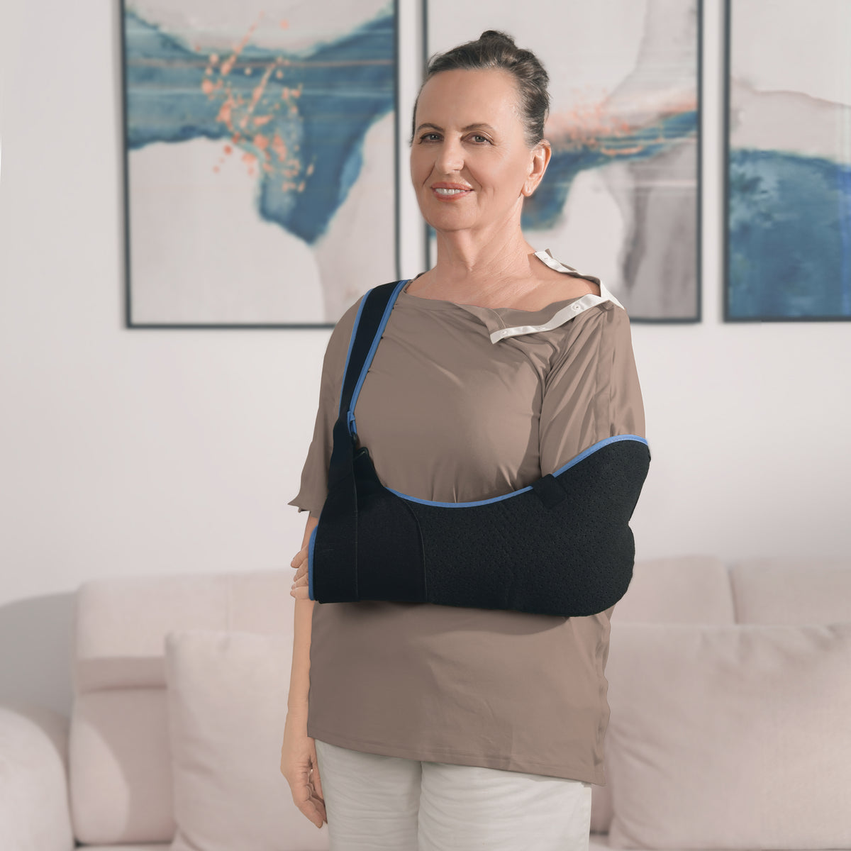 Woman wearing a Khaki side-snap shirt with shoulder snaps open and an arm sling.