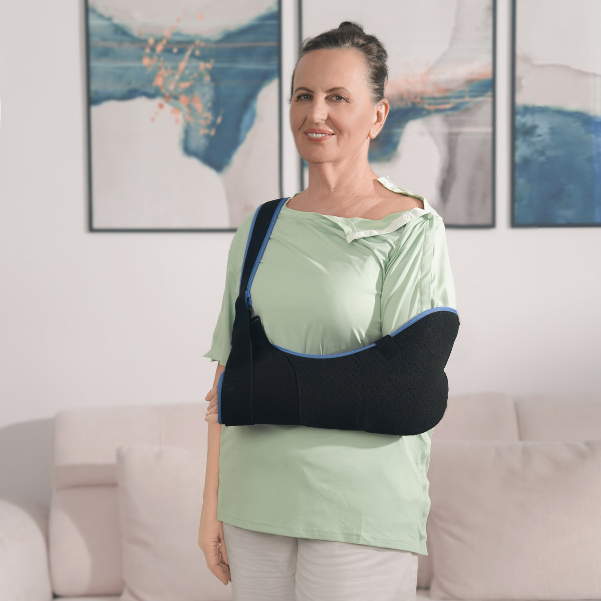 Woman wearing a Sage Green side-snap shirt with shoulder snaps open and an arm sling.
